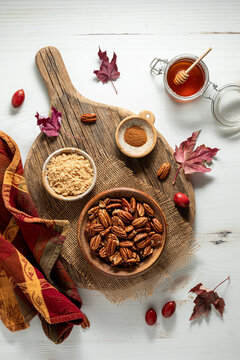 A bowl of caramelized pecans with ingredients used for making them and fall decorations all around.