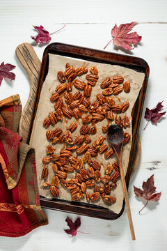 Caramelized pecans spread out on a parchment lined baking sheet to cool