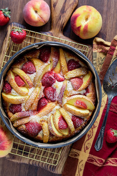 Above view of a strawberry peach cake hot out of the oven on a cooling rack.