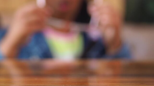 Childs pink eyeglasses being picked up from table surface close up view