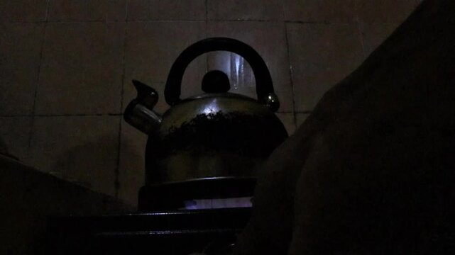 Close-up footage of a metal kettle heating water on a gas stove in a traditional home kitchen, showing a simple daily cooking activity.