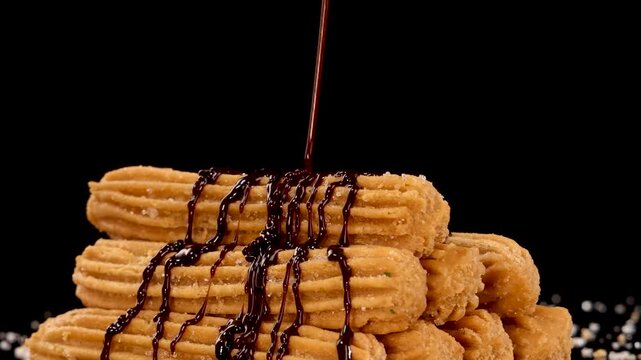 Hot chocolate sauce pouring over stack of churros sweet dessert for delicious treat.