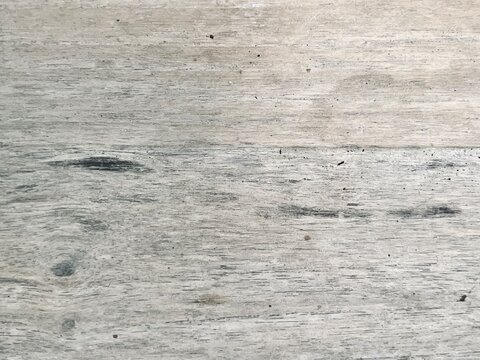 Close-up view of a light grey weathered timber board showing natural wood grain and dark knots.