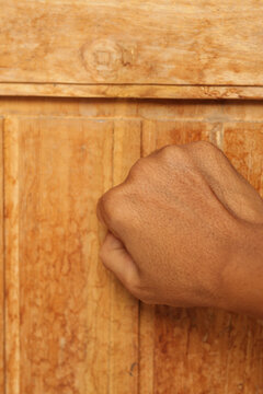 Close up of a person hand knocking on a wooden door, guest visiting, privacy, and opportunity concept.