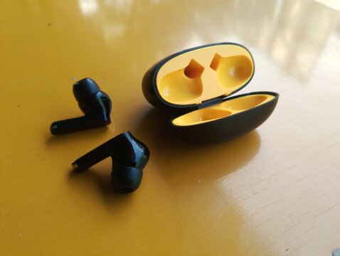 Wireless Earbuds and Charging Case on Wooden Table