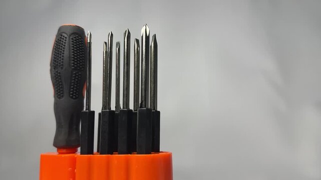 Interchangeable screwdriver bit set with orange handle in holder