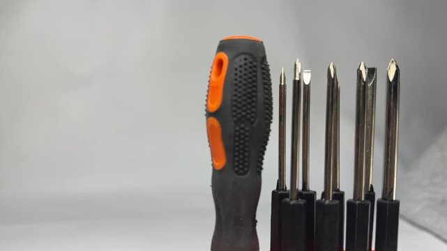 Interchangeable screwdriver bit set with orange handle in holder
