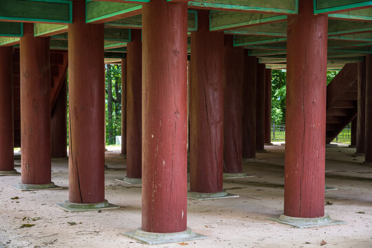 Red wooden pillars supporting a traditional Korean pavilion with painted Dancheong beams on stone bases in south korea.