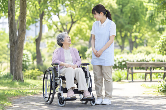 Elderly Japanese woman in a wheelchair with a male caregiver outdoors