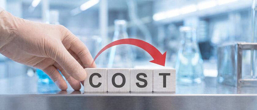 A person in a laboratory setting arranging wooden blocks that spell out the word cost, symbolizing expenses or financial investment in scientific research