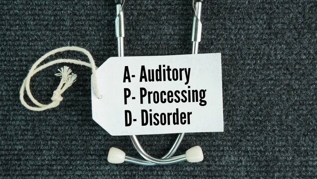 Stethoscope and paper tag with the words Auditory processing disorder APD. condition where the brain struggles to make sense of sounds and speech even though a person has normal hearing