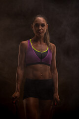 Obraz premium Fitness enthusiast in athletic attire performing exercise with focused expression in atmospheric lighting
