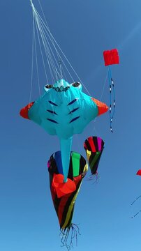 Giant colorful show kites with spinning windsock cones in blue sky