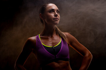 Obraz premium Strong and confident woman in athletic wear against a dramatic smoky background