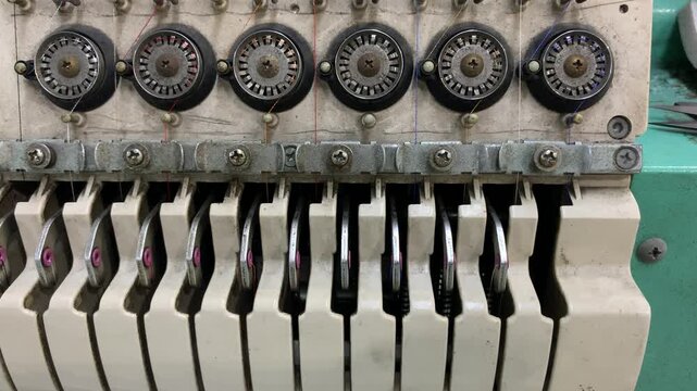 Close up of a multi thread textile machine featuring tension control assemblies used in industrial sewing and embroidery operations