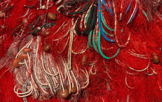 Italy, Sardinia, Bosa.  Brightly coloured fishing nets piled up on a dock in the harbour.