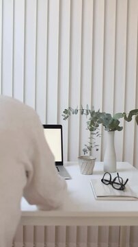Faceless Remote Worker Using Laptop at Elegant Home Office Desk with Vase and Beautiful Flowers