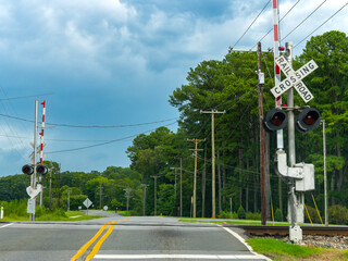 Rural railroad crossing with warning signals along an asphalt road, ideal for transportation infrastructure, railway safety concepts, and rural travel themes. © Julio