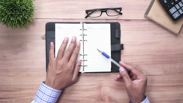 Hands opening notebook and preparing to write with pen, close up