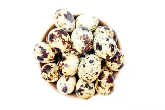 Top view A collection of speckled quail eggs in a brown bowl isolated on a white background.