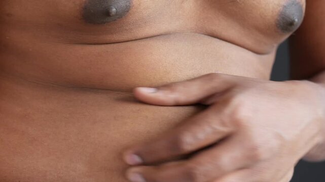 Close up of man pinching belly fat showing excess weight and health concerns