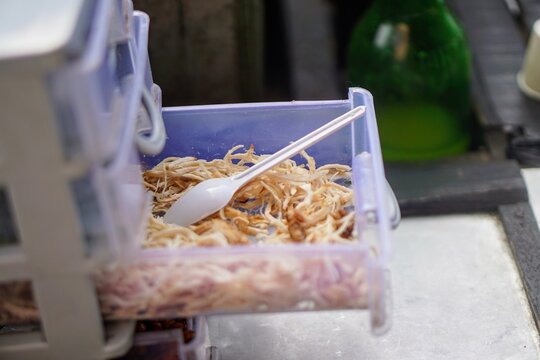 Close-up shot of delicious shredded chicken meat inside a transparent plastic storage drawer of a porridge vendor