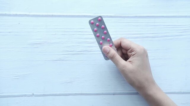Close up of person hand holding medical pills strip pack isolated on white background healthcare and medicine concept
