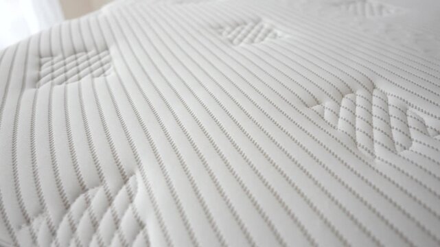Close up moving over white striped mattress surface with quilted pattern detail