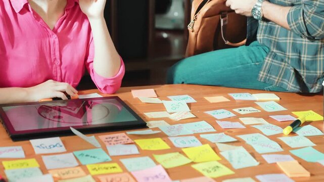 Close up of project manager hands shaking hand with businessman at meeting table with sticky notes and tablet displayed logo design. Business team working together and talking about idea. Symposium.