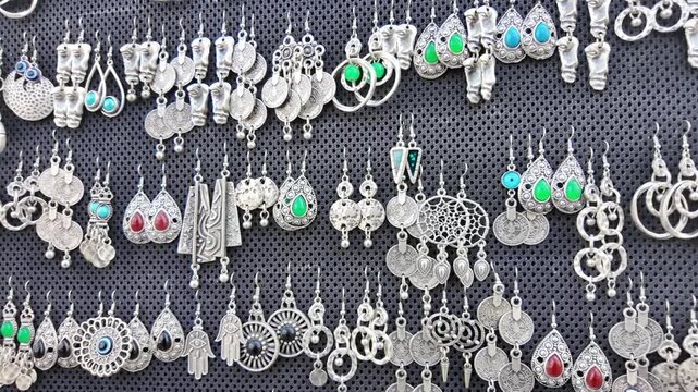 Selection of ethnic handmade earrings dangle with intricate designs displayed on textured dark background