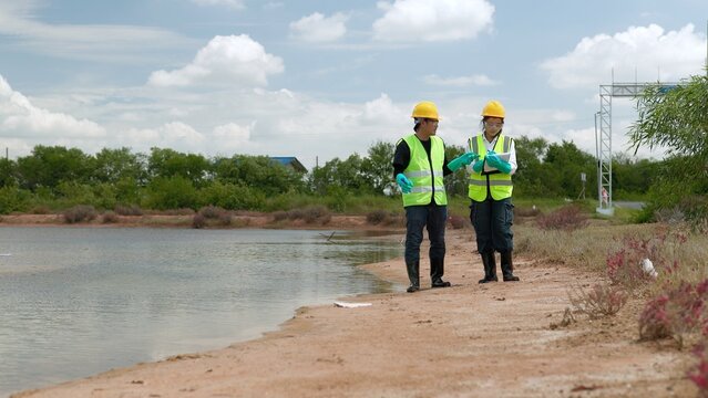 Certified Environmental Inspectors in Safety Gear Consulting Beside Lake Shoreline on Water Conservation 4K