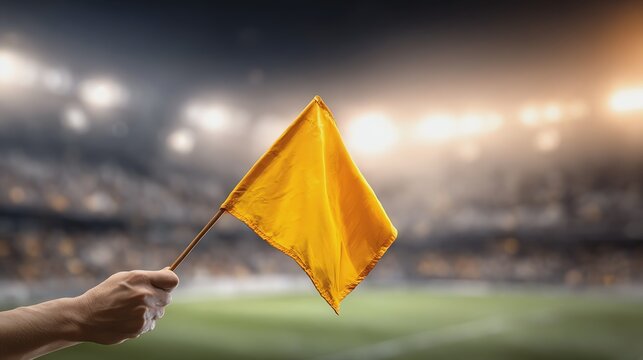 Hand holding yellow flag at sports event.