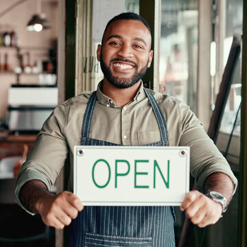 Startup, portrait or happy man with open sign in cafe for small business or welcome entrance. Male person, entrepreneur or owner with smile, billboard or ready for service in coffee shop restaurant
