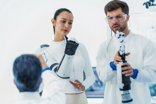 Sensor driven robotics research: a colleague lifts her hand toward the gripper of an upright robotic arm so the proximity sensors can register an approaching palm