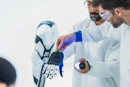 Collaborative robotics testing: a researcher fingertip meets the black mechanical fingertip of a laboratory robot hand, framing safe contact between people and machines