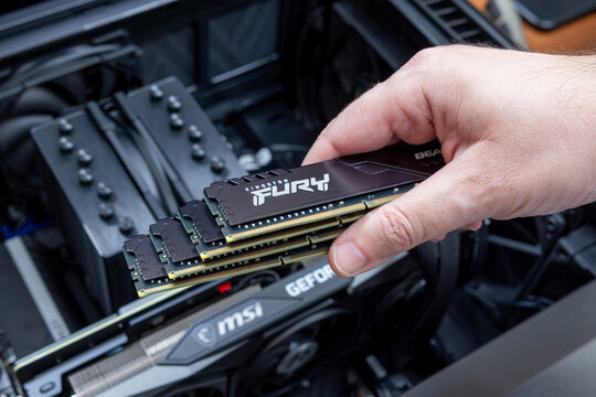 Technician holds four Kingston Fury DDR modules. GeForce graphics card is visible. High-performance components for computer upgrade. Pavlodar, Kazakhstan - December 15, 2025