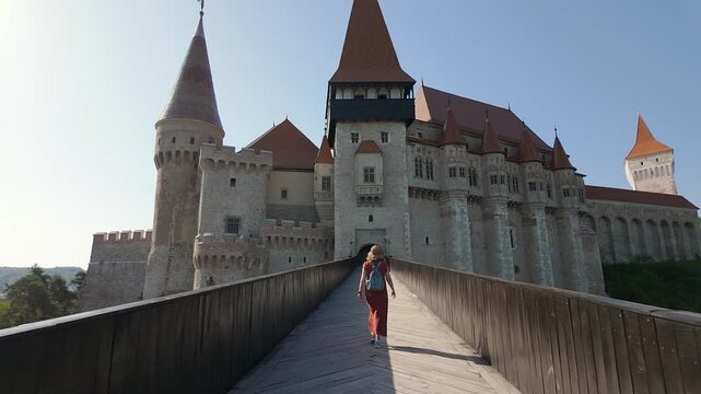 Woman tourist walking across the bridge toward Corvin Castle in Hunedoara Romania