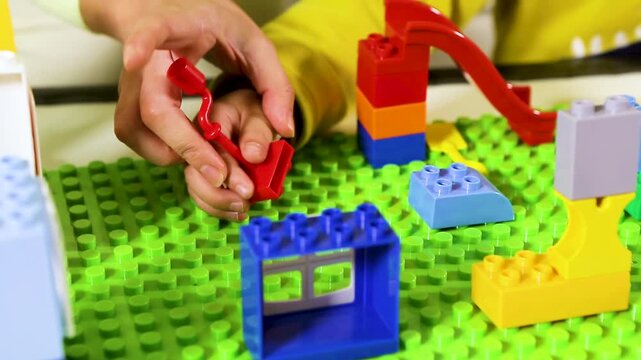 Close-up of someone building a plastic brick house.