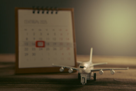 Airplane model and calendar on wooden background. Travel planning concept.