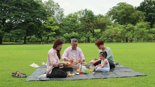food and drinks. Happy Asian family having fun time on picnic at city nature park, outdoor activitie