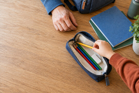 Kind sortiert mit einem Elternteil Buntstifte ins Schuletui
