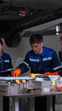Automotive technicians work together during vehicle inspection and maintenance inside a professional workshop. The scene emphasizes collaboration, technical expertise, vehicle servicing, mechanical en
