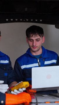 A professional group of automotive technicians works together inside a modern repair facility. The image represents teamwork, skilled labor, automotive maintenance, mechanical expertise, technical col