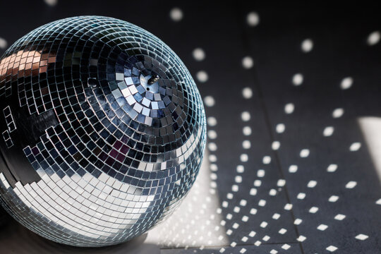 Shiny disco ball reflects light on dark surface