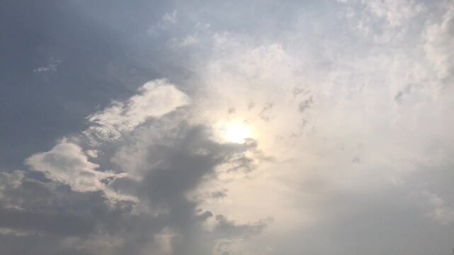 Bright sun shining through fast moving white clouds in blue sky, cinematic time lapse. Stunning  time lapse of bright blue sky with first moving white clouds and sun shine.