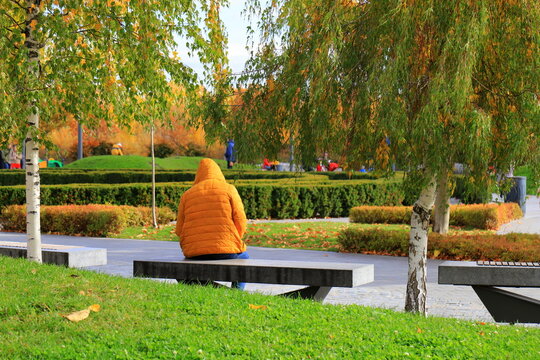 A man resting on a bench in an autumn park, autumn landscape in the city