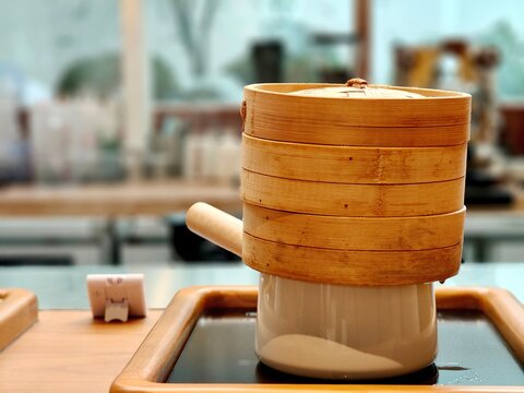 Stacked bamboo steamer on ceramic pot in a modern kitchen, showcasing traditional Asian cooking and steam food preparation.