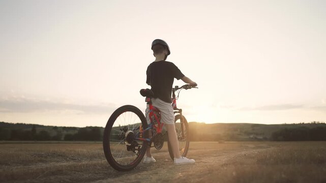 Little child learning to ride bike in country, back view of boy on bicycle. Merry childhood moments, carefree preteen spending summer weekend in nature, active lifestyle, children play outdoors