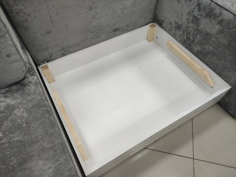Open drawer box with wooden support bars inside a grey upholstered sofa mechanism