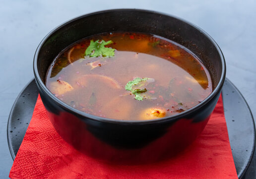 Tom yum thai soup with chicken in black bowl